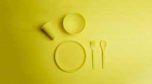 una tavola gialla con piatto, forchetta e cucchiaio