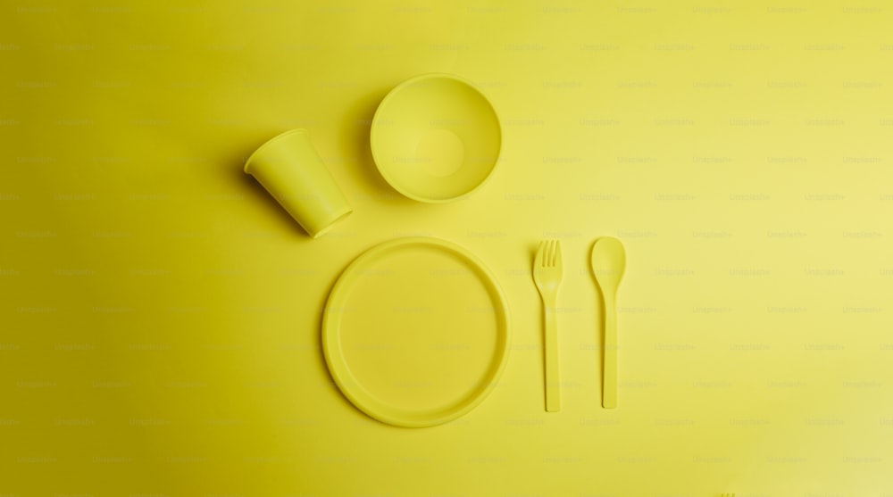 접시, 포크, 숟가락이 있는 노란색 테이블 세팅