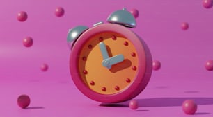 Un despertador rosa rodeado de bolas rosadas