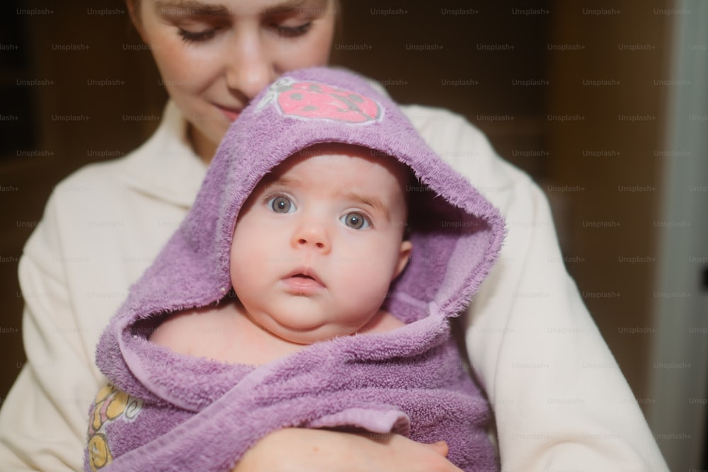 a woman holding a baby wrapped in a towel