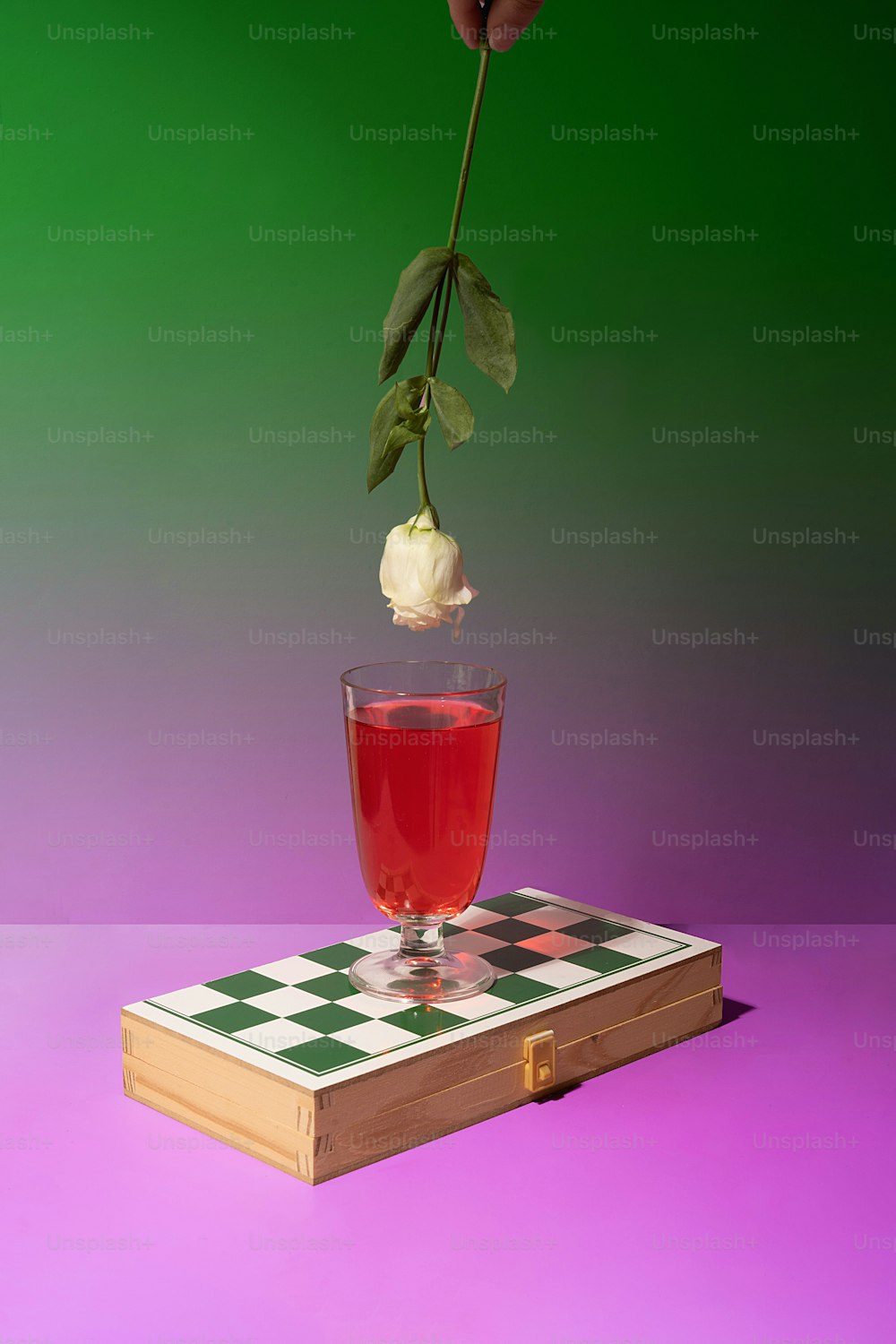 Eine einzelne Rose in einem Glas Tee auf einem Buch
