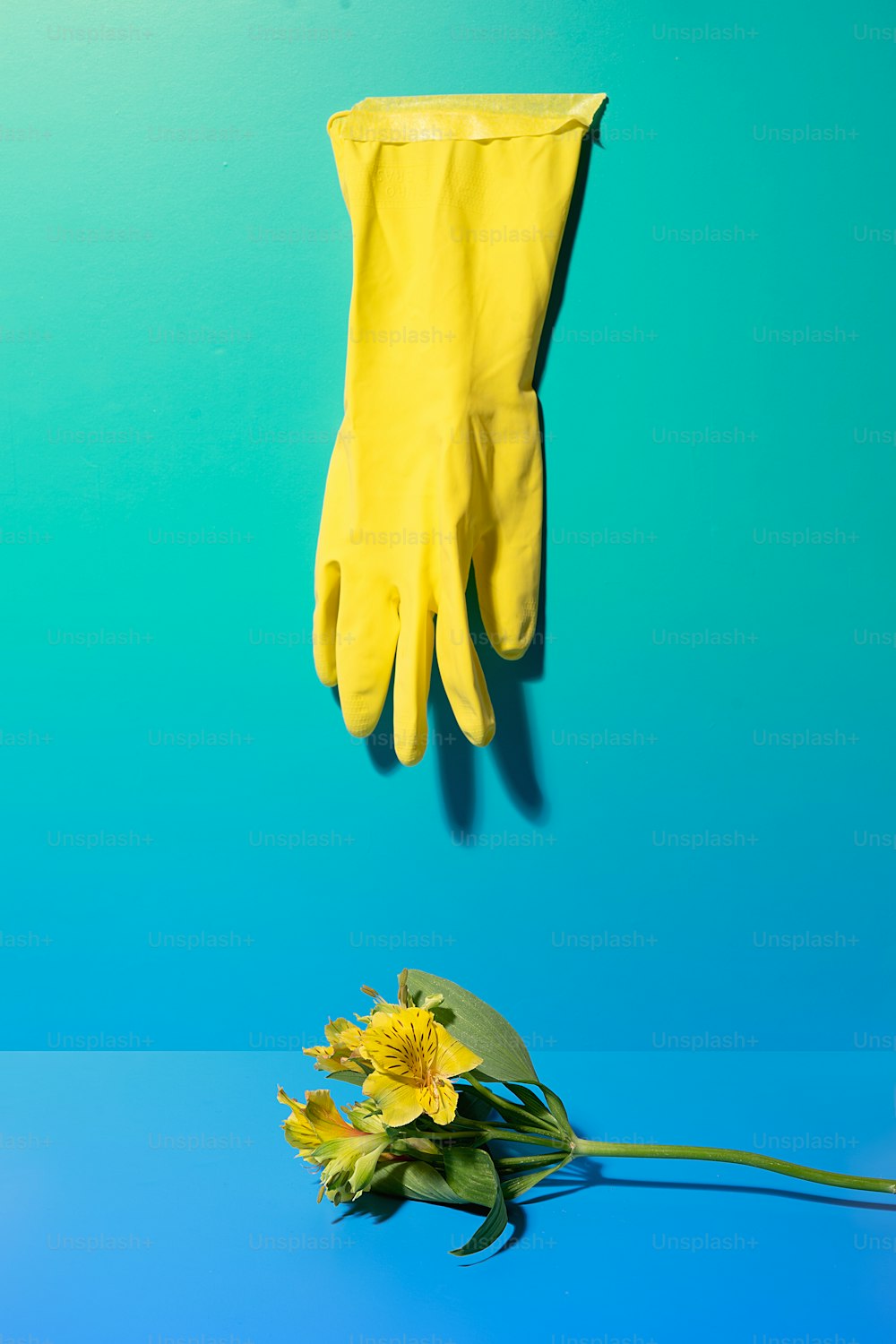 a pair of yellow gloves and a yellow flower on a blue background