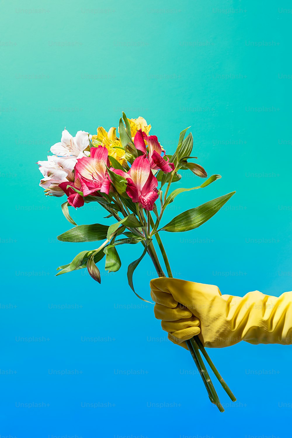 une personne portant des gants de caoutchouc jaunes tenant un bouquet de fleurs