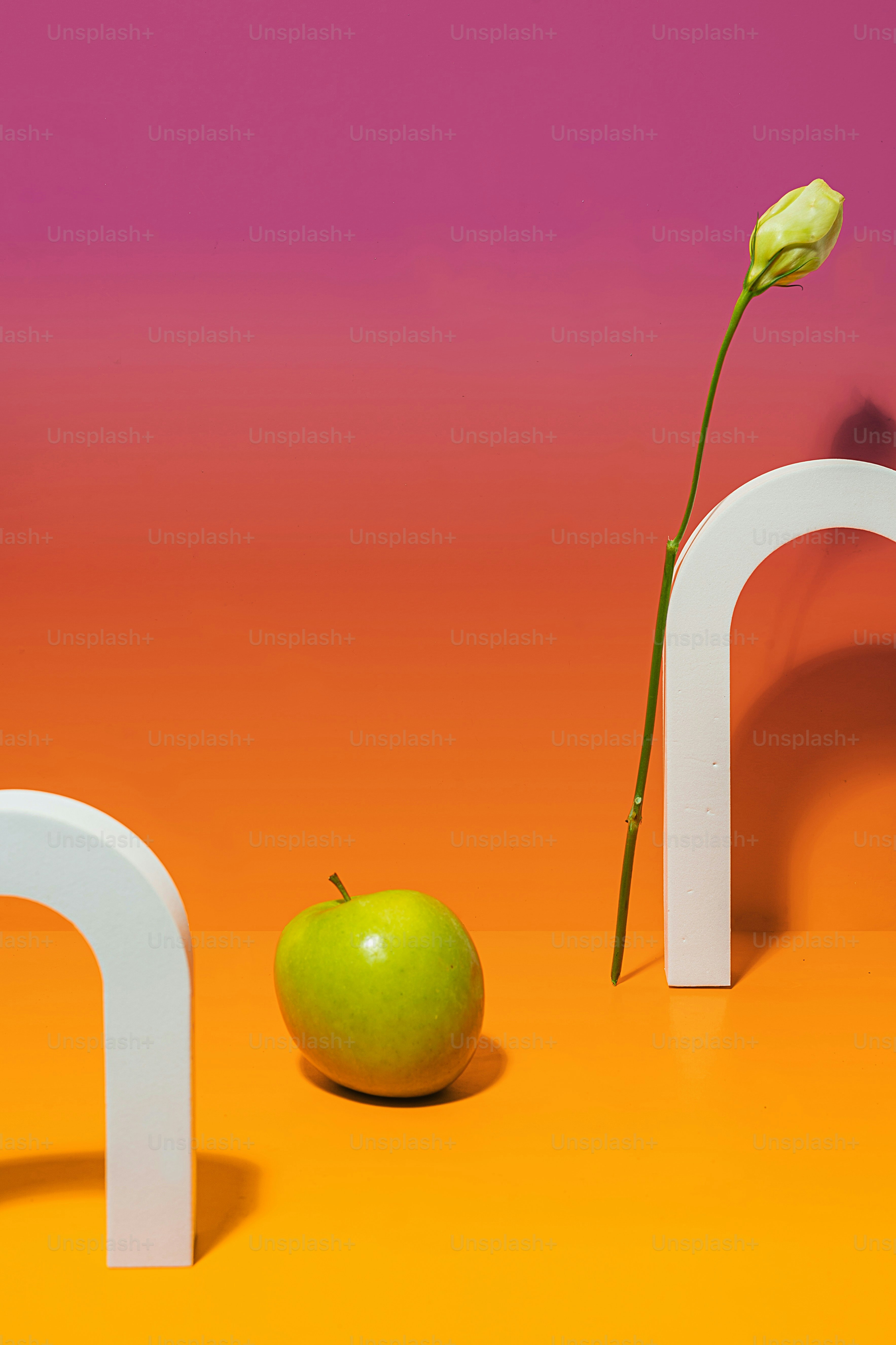 uma maçã verde sentada ao lado de um arco branco