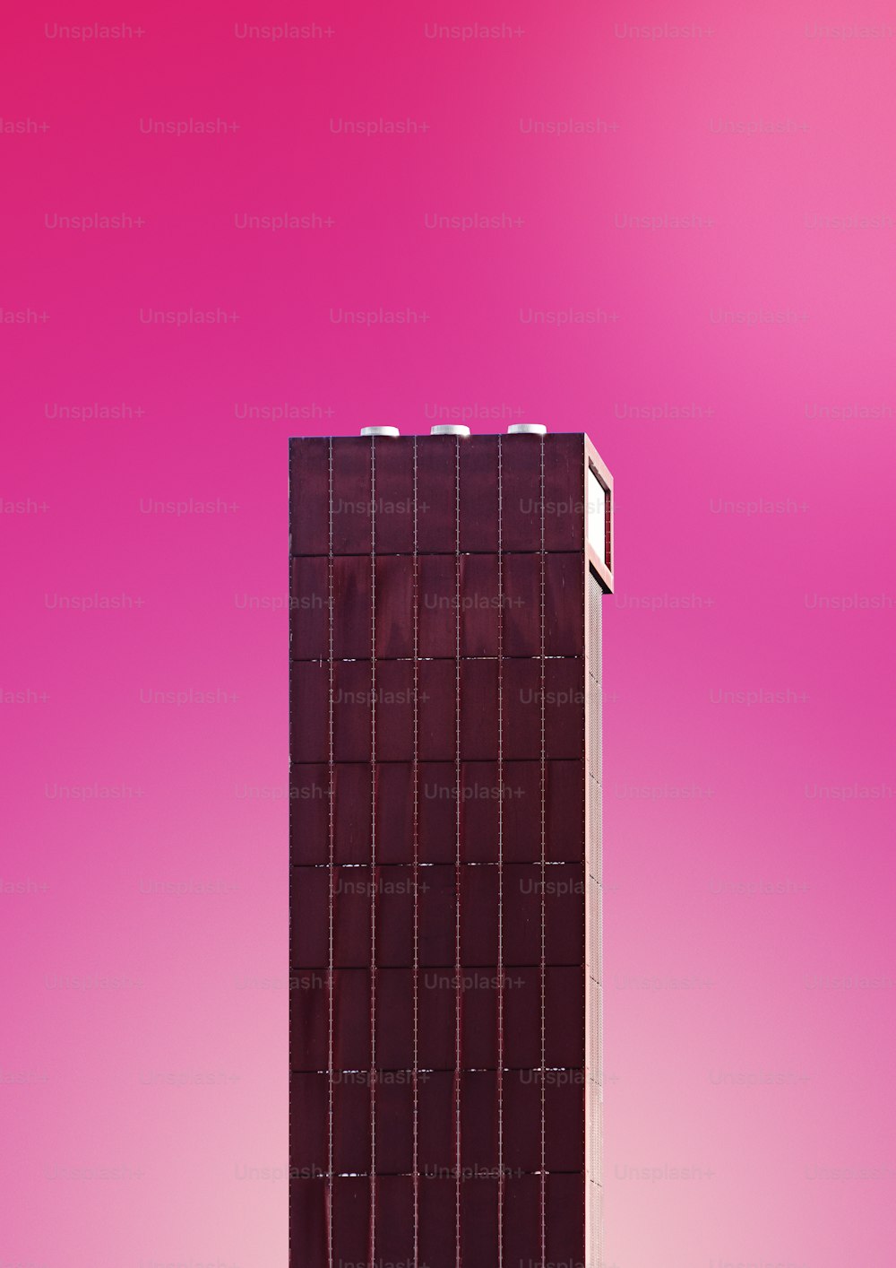 Un alto edificio marrone con uno sfondo rosa
