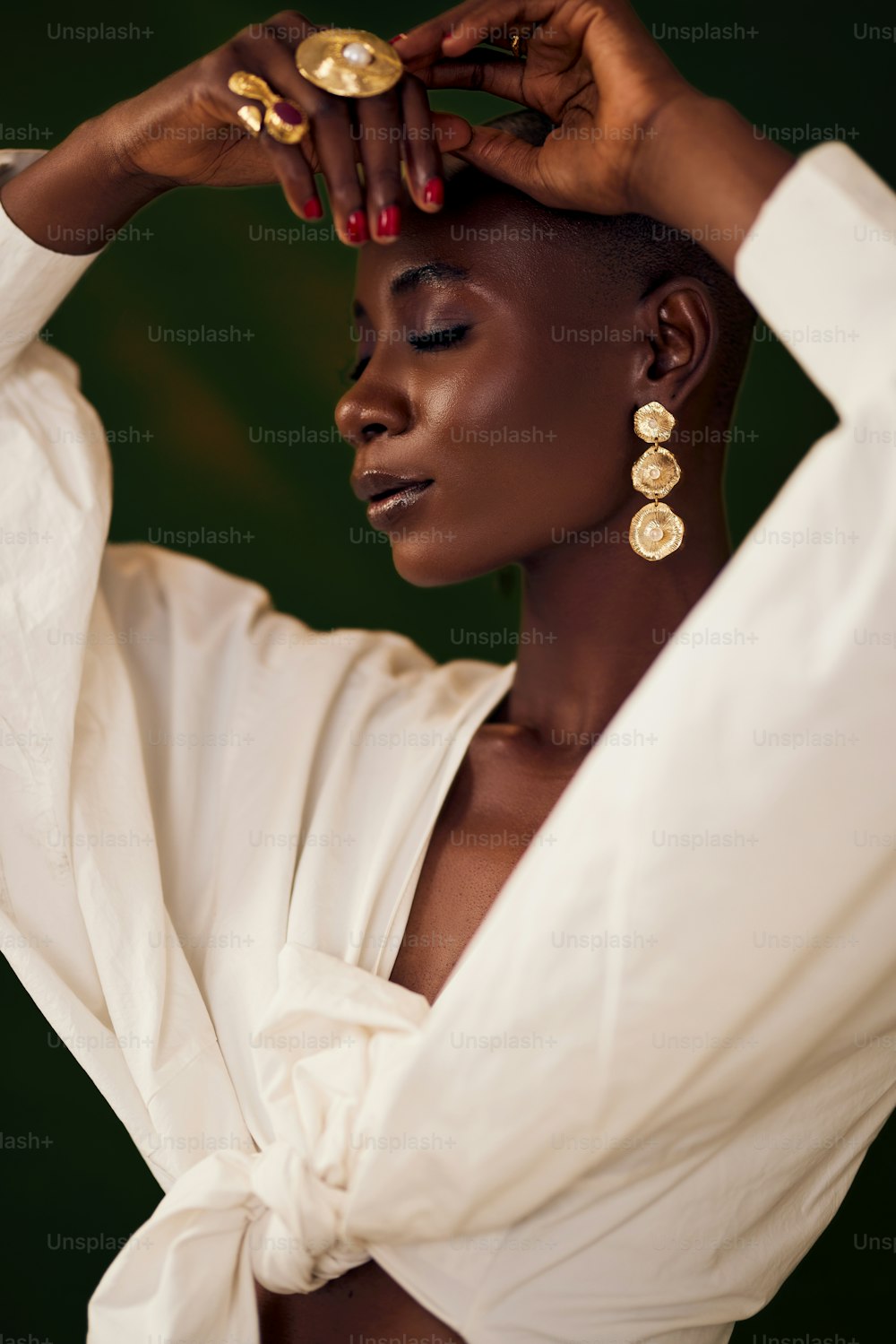 a woman in a white shirt and gold earrings
