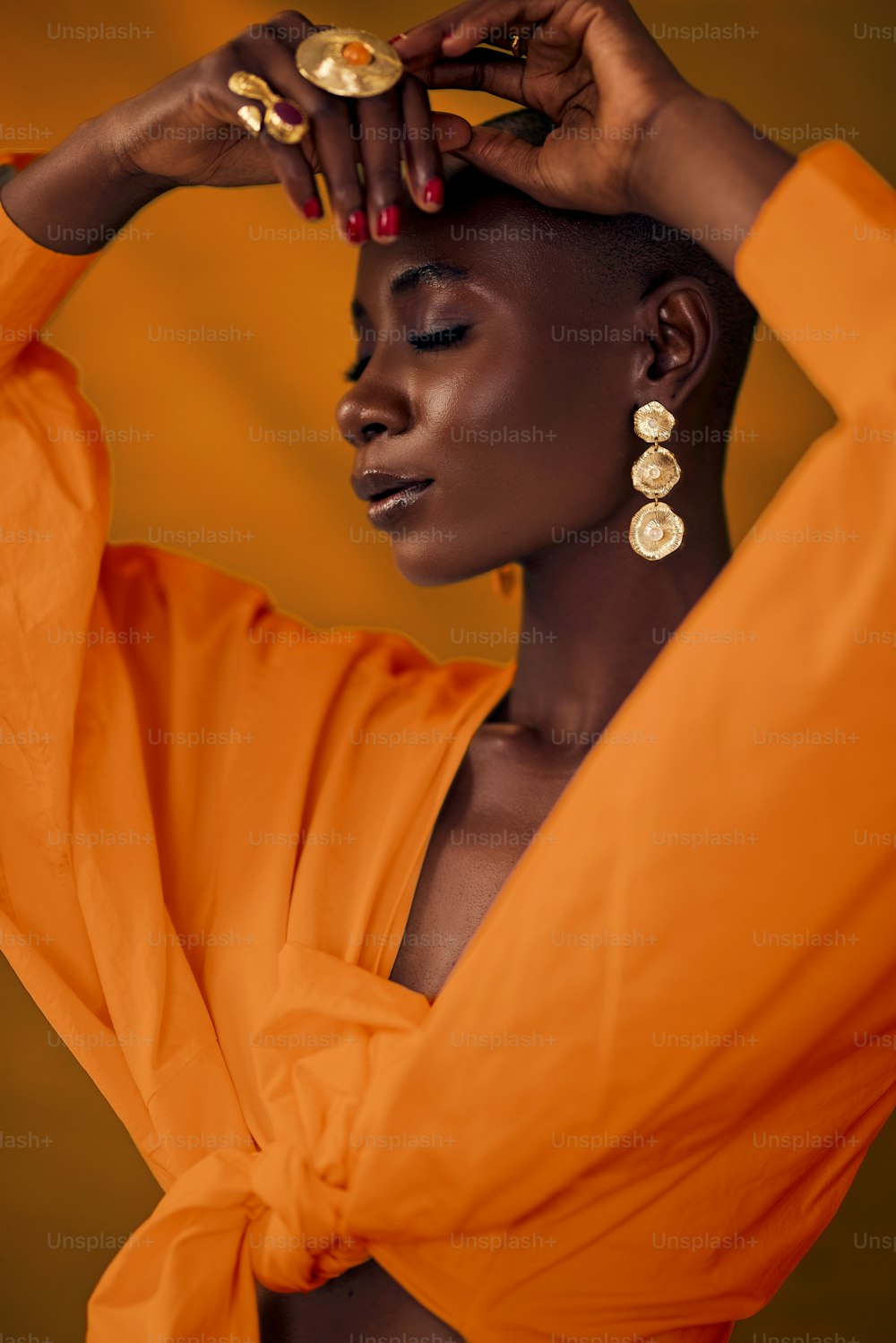 a woman in an orange dress holding her hair
