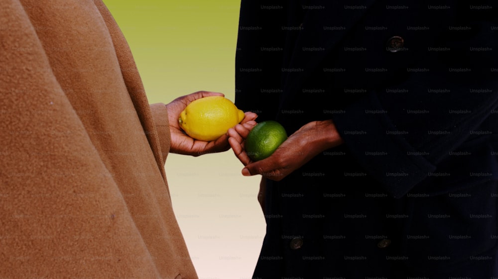 a man holding a lemon and a lime in his hand