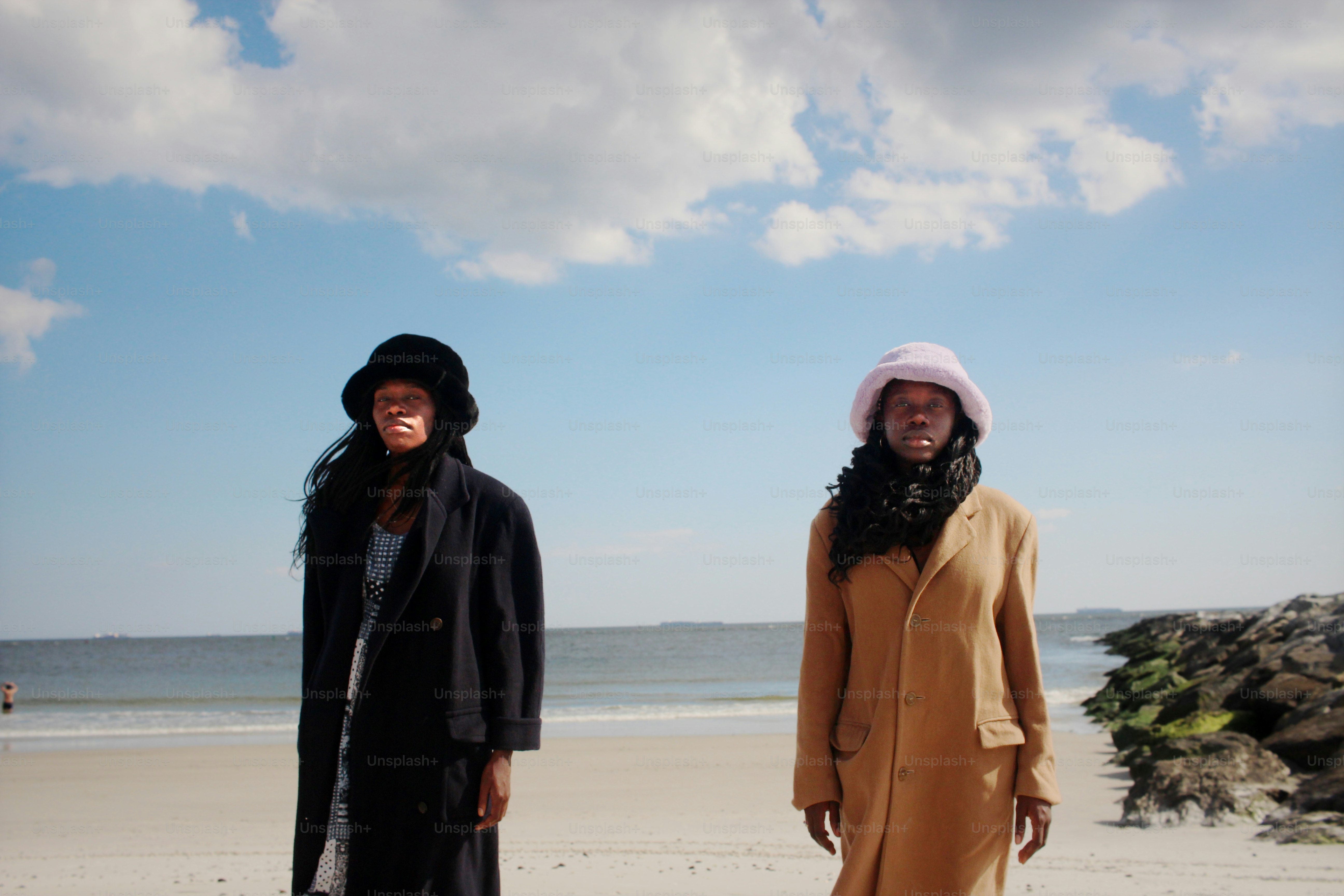 a couple of women standing on top of a sandy beach