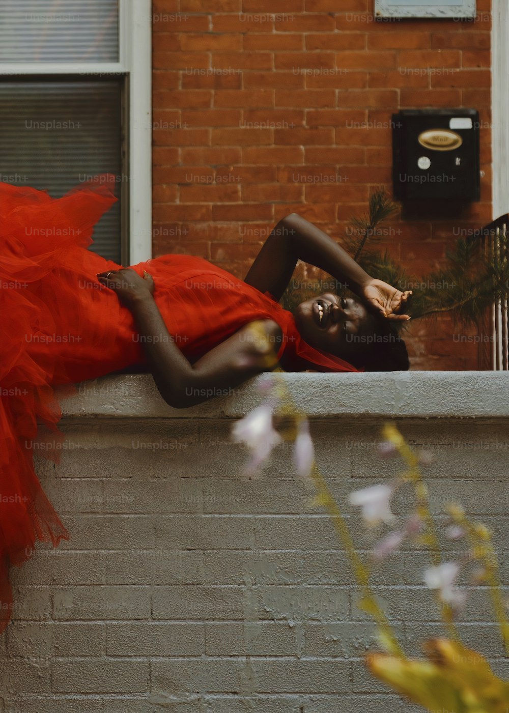a woman in a red dress laying on a ledge