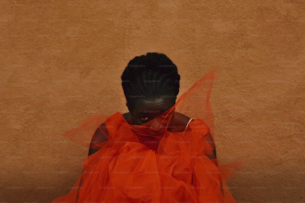 Eine Frau in einem orangefarbenen Kleid sitzt auf dem Boden