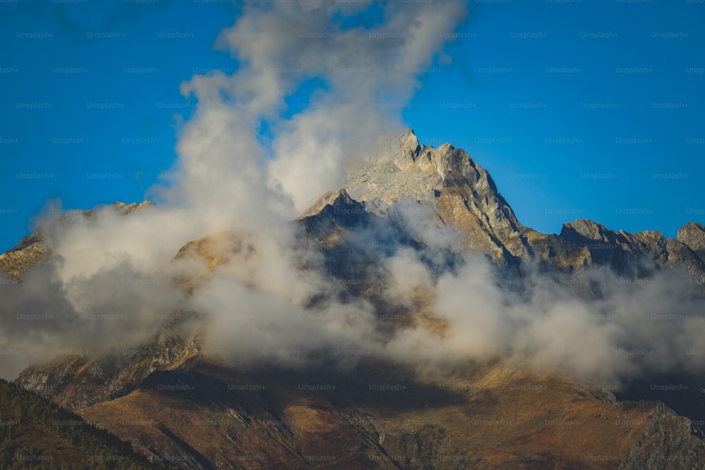 a mountain covered in clouds with a blue sky in the background