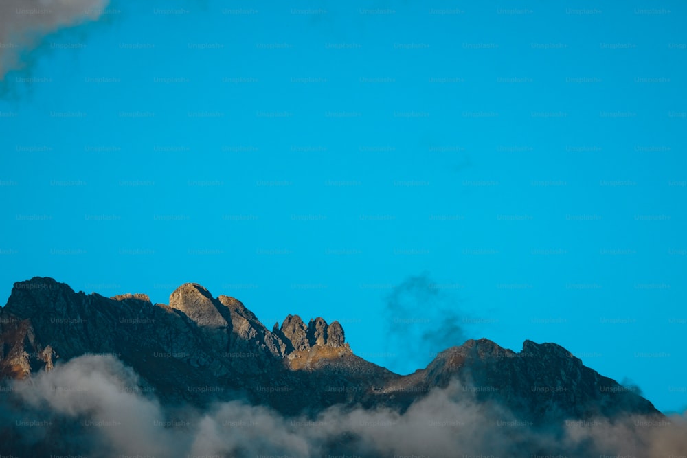 uma vista do topo de uma montanha com nuvens em primeiro plano