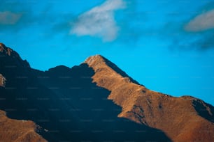 a plane flying over a mountain range under a blue sky