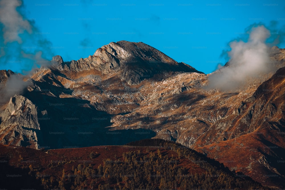 a view of a mountain range with clouds coming out of it