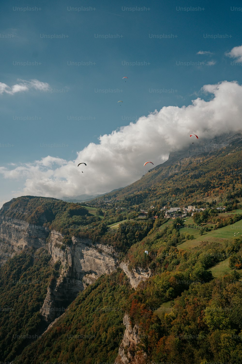 a group of people flying kites over a lush green hillside