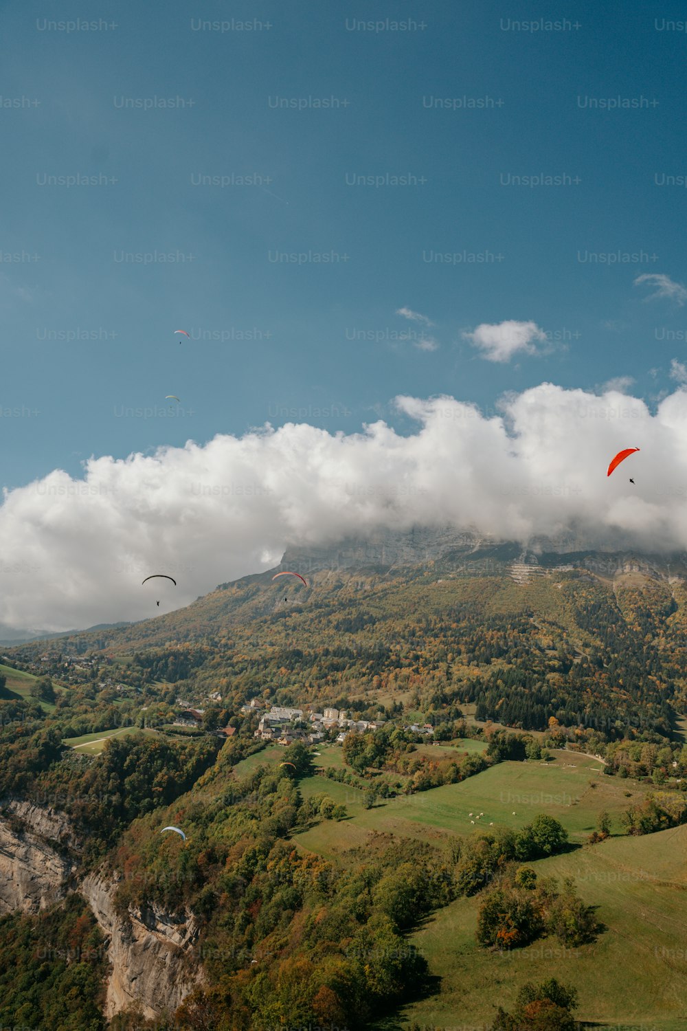 a group of people flying kites over a lush green hillside