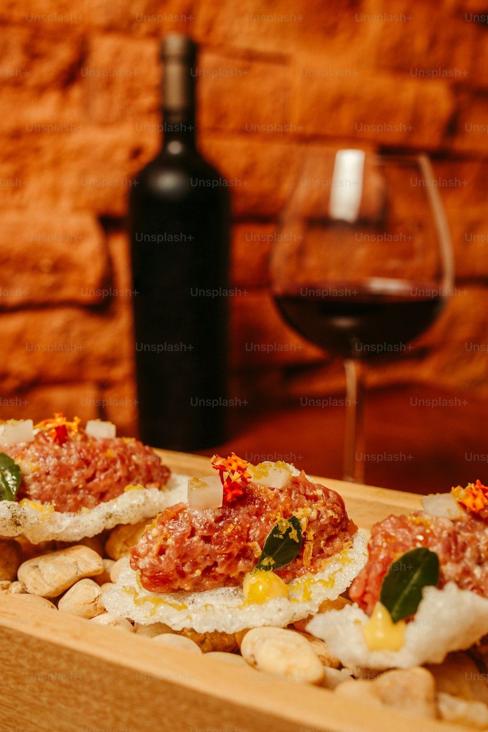 a wooden box filled with food next to a glass of wine