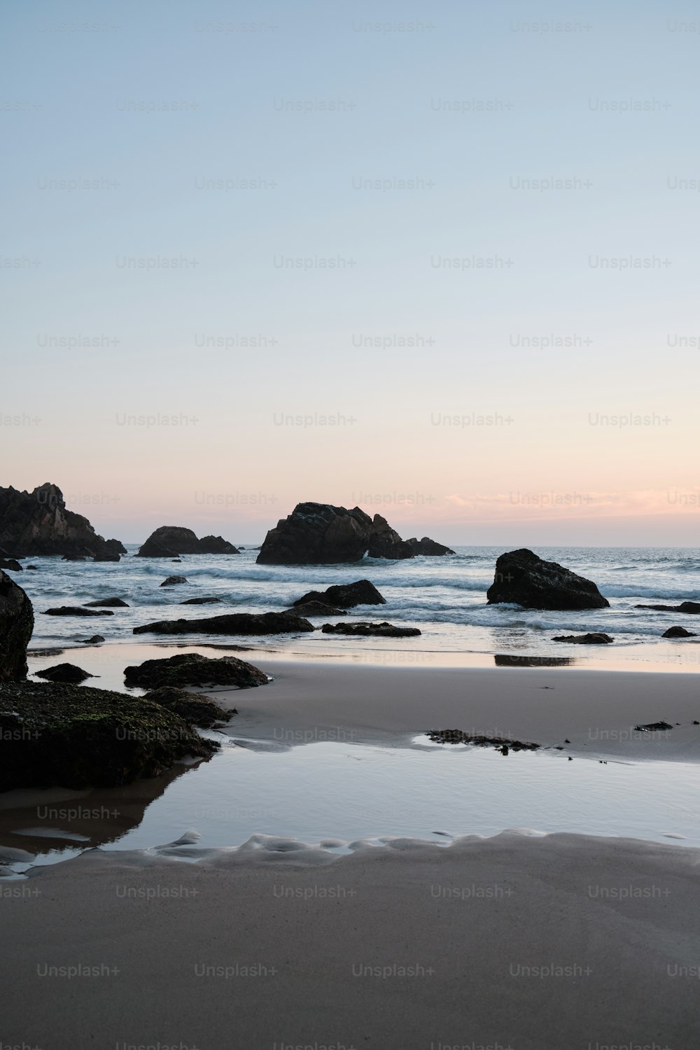 a beach with rocks and water at sunset