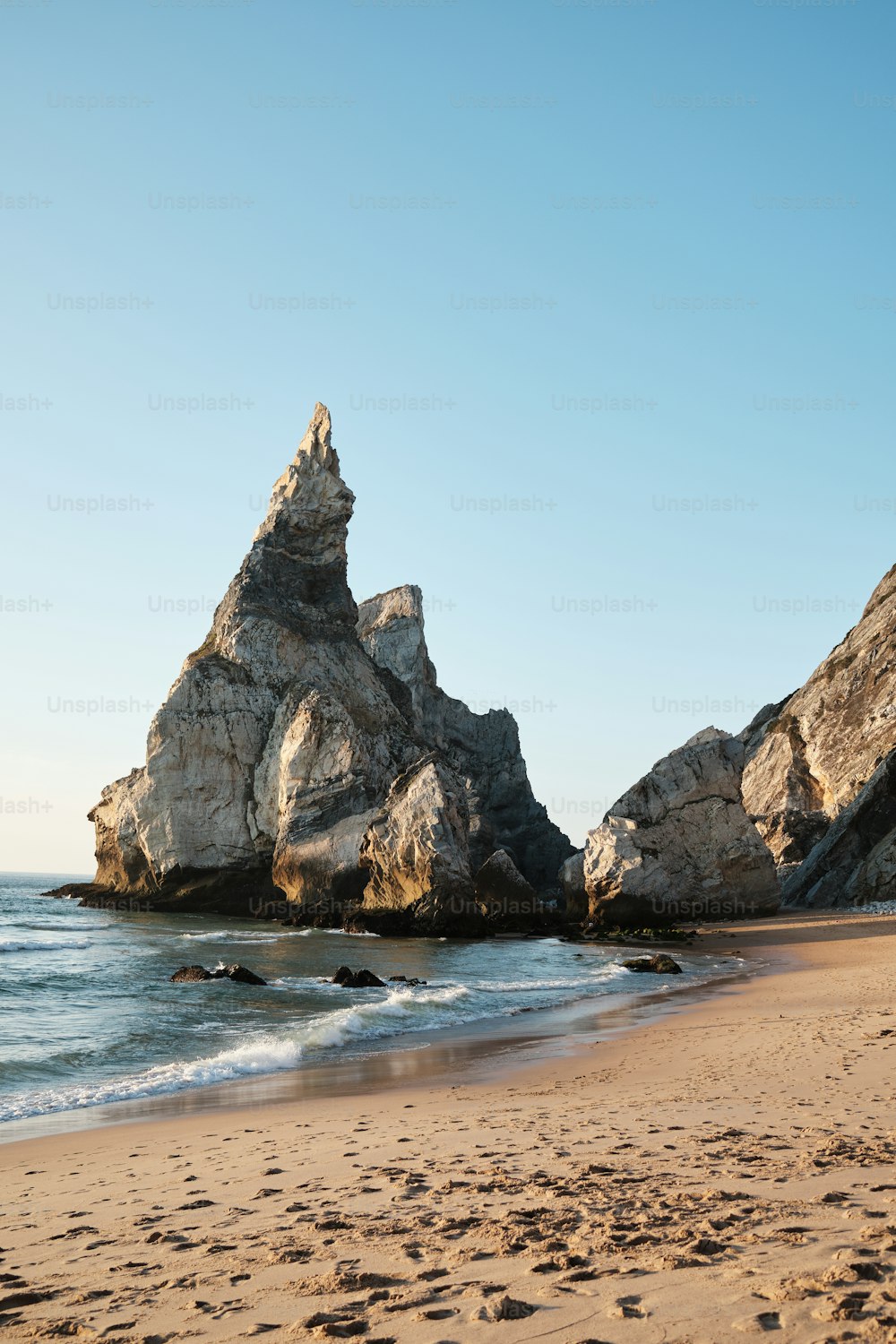 a rocky outcropping on a beach next to the ocean
