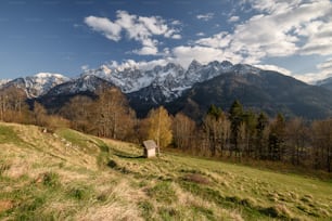 a small hut on a grassy hill with mountains in the background