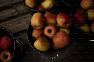 four buckets of apples sitting on a wooden table