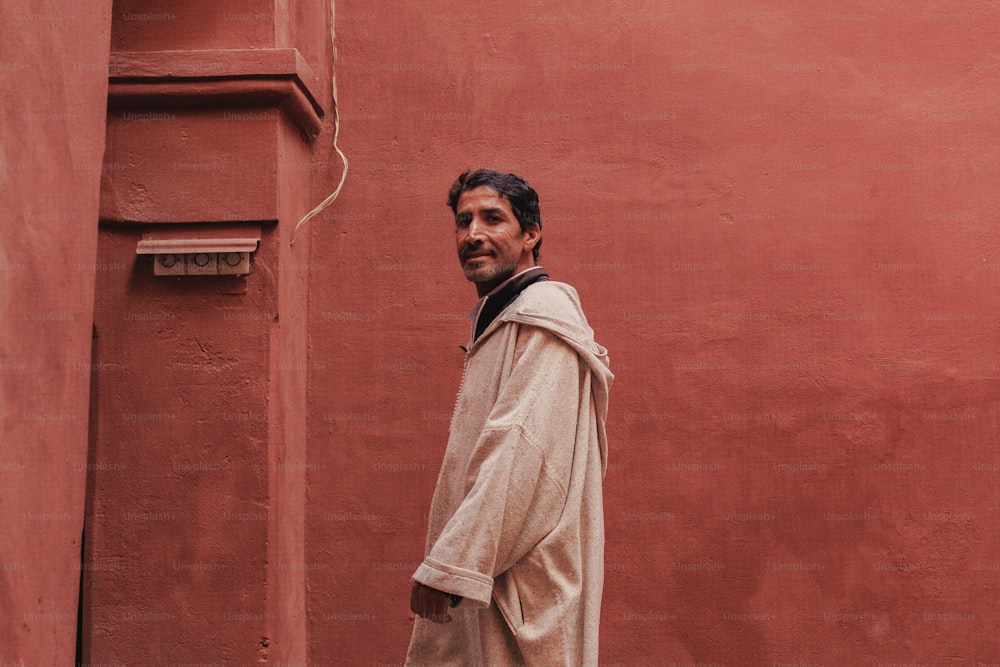 a man standing in front of a red wall