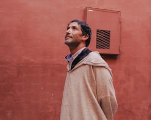 a man standing in front of a red wall