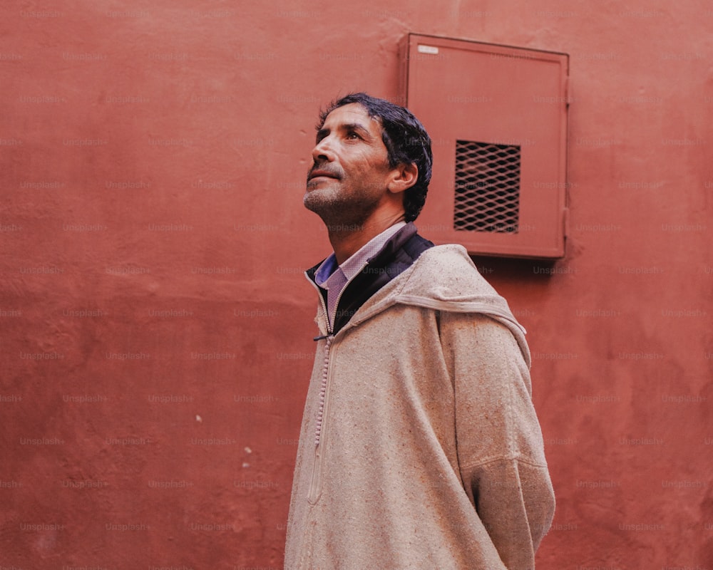 a man standing in front of a red wall