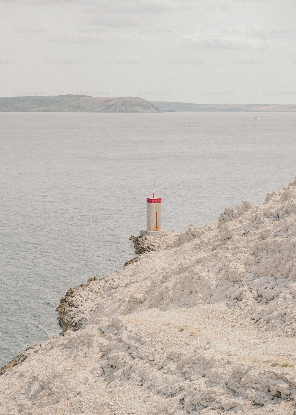 Un phare rouge et blanc assis au sommet d’une falaise