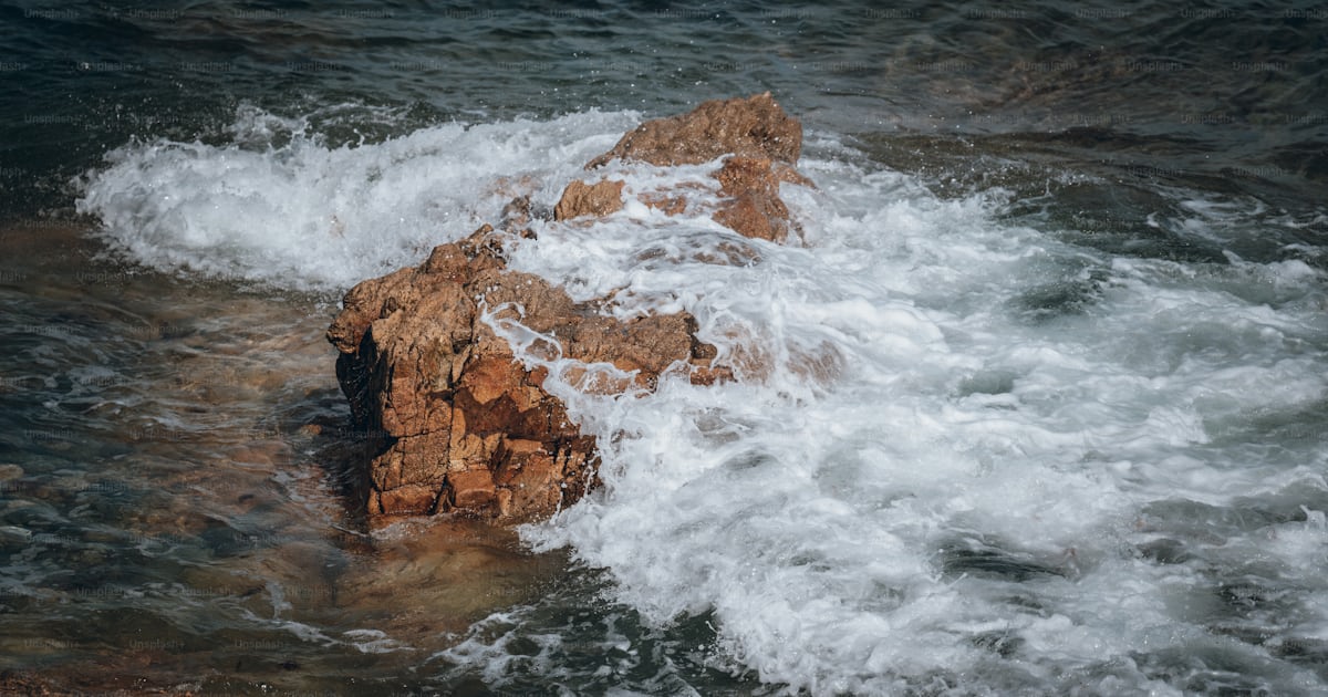 Foto Una roca en medio del océano – Bretaña Imagen en Unsplash