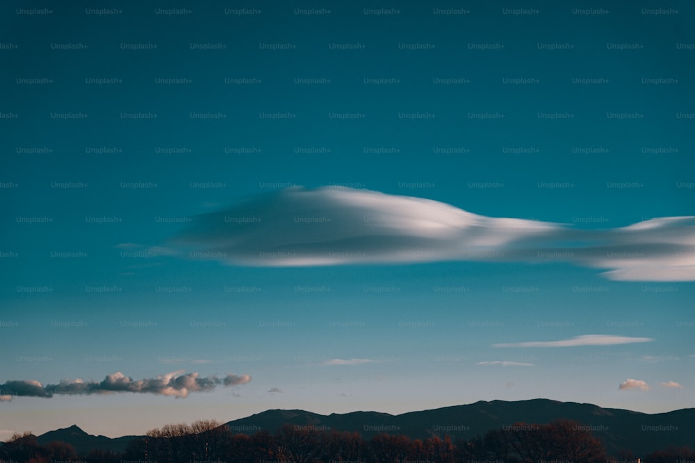 a large cloud is in the sky over a mountain