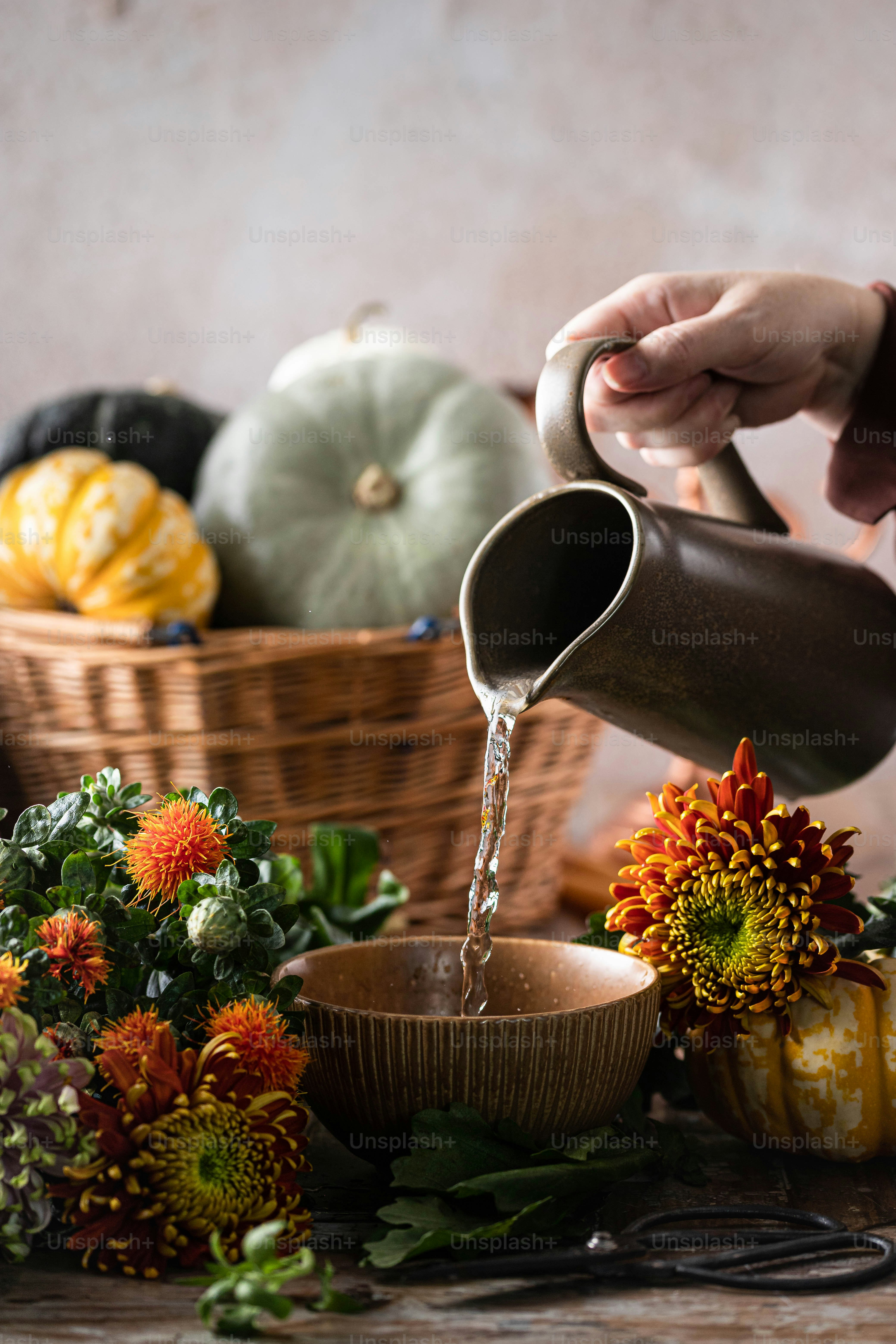 a person pouring water into a bowl of flowers