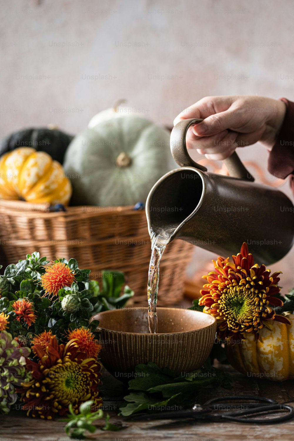 a person pouring water into a bowl of flowers