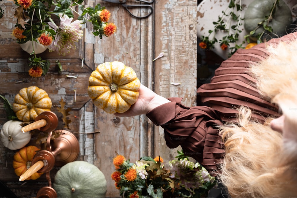 a woman holding a pumpkin in front of a bunch of pumpkins