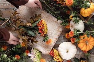 a person arranging flowers and pumpkins on a table