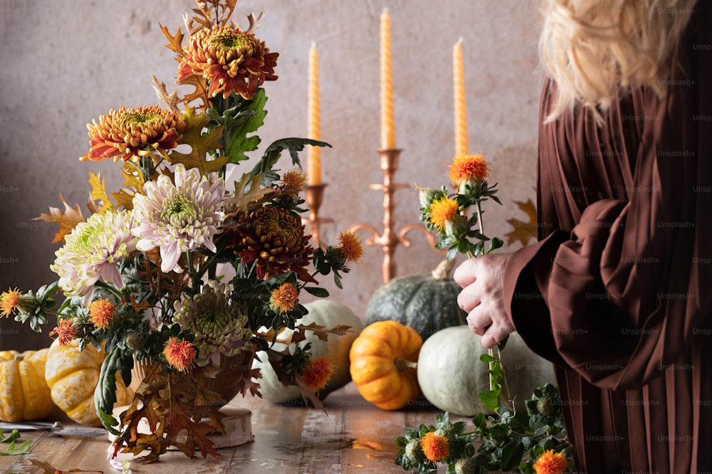 한 여자가 탁자 위에 꽃과 촛불을 정리하고 있다