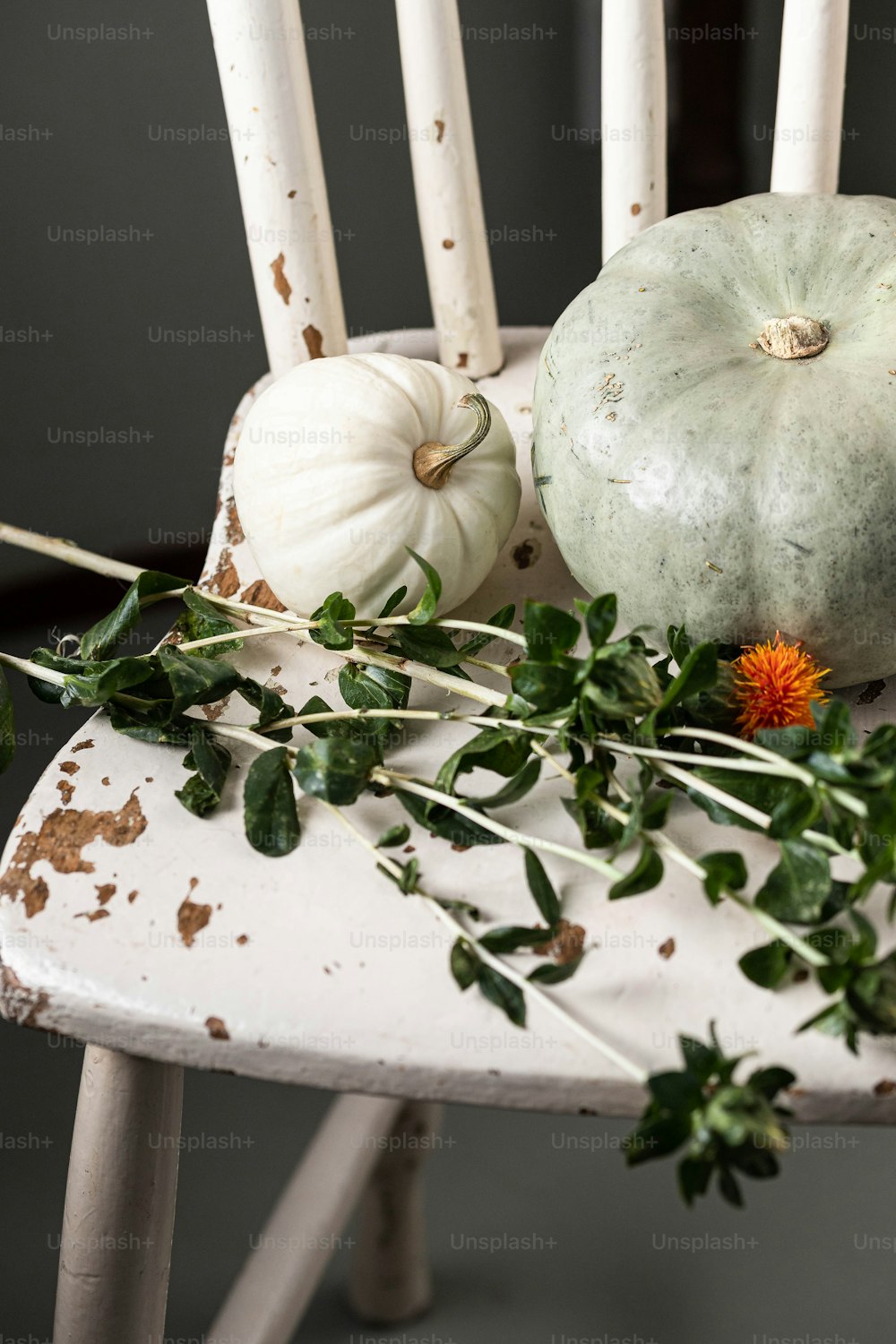 a white chair with a bunch of flowers and pumpkins on it