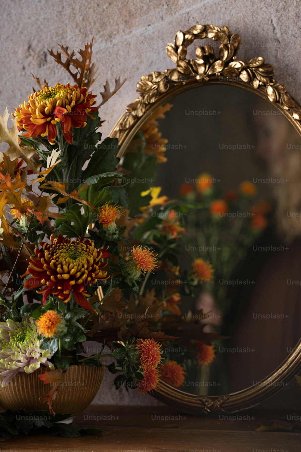Un espejo sentado encima de una mesa junto a un jarrón lleno de flores