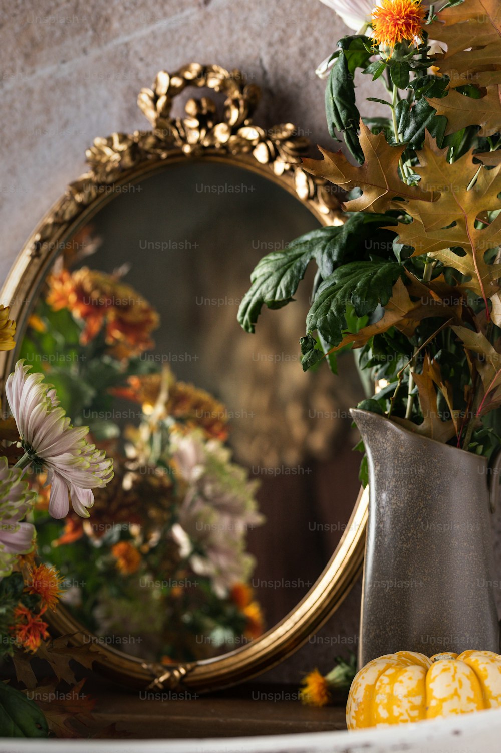 eine Vase mit Blumen und ein Spiegel auf einem Mantel