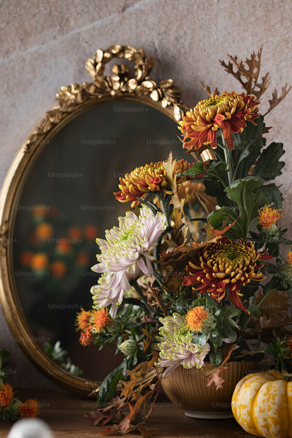 eine mit Blumen gefüllte Vase neben einem Spiegel