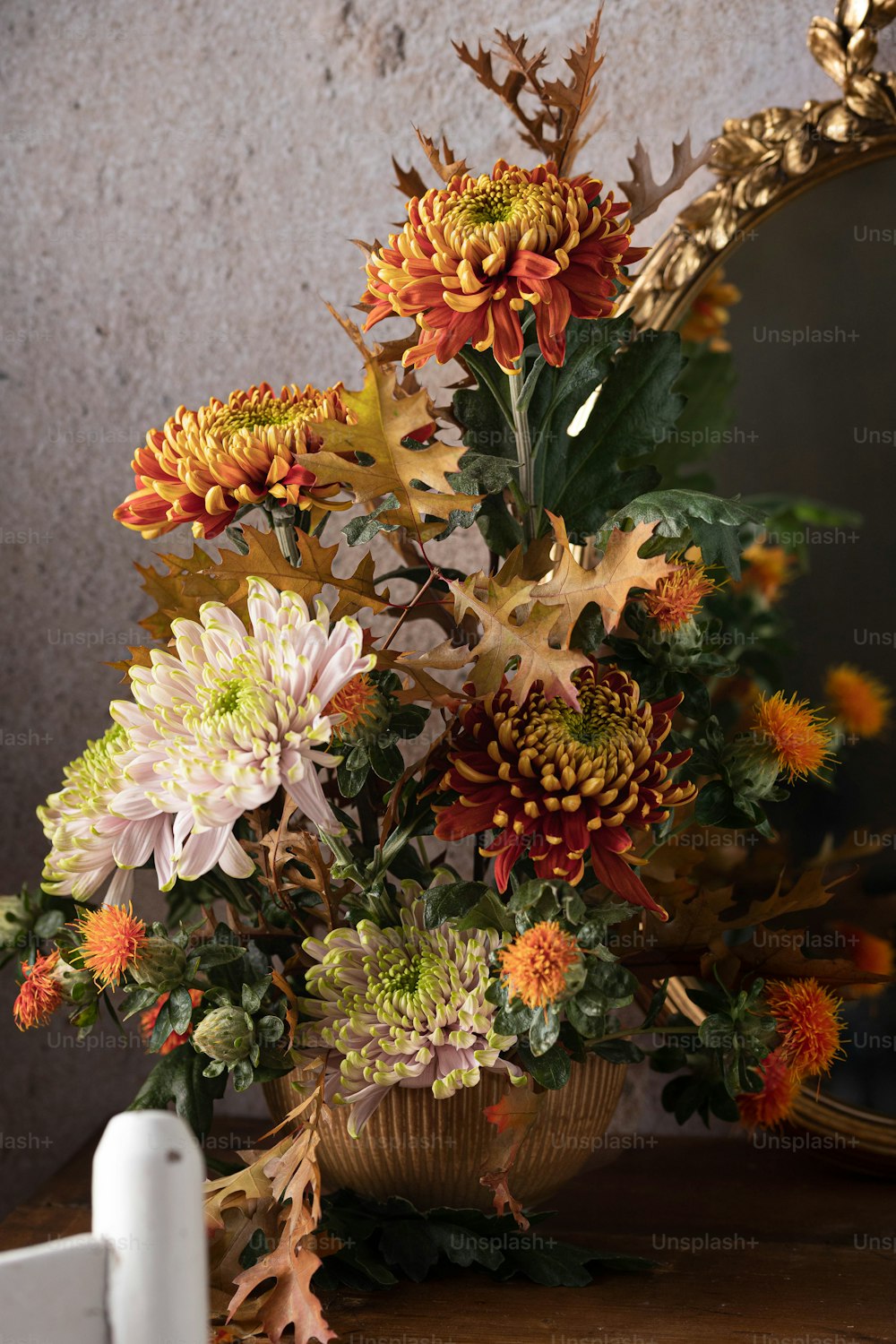 eine Vase gefüllt mit vielen Blumen neben einem Spiegel