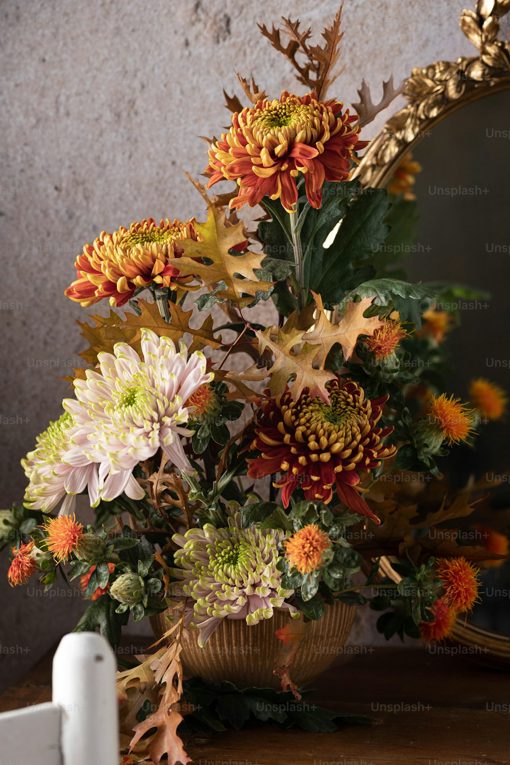Un vase rempli de beaucoup de fleurs à côté d’un miroir