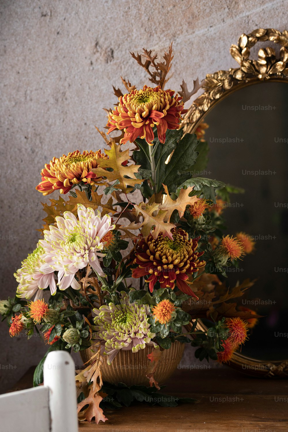 eine Vase gefüllt mit vielen Blumen neben einem Spiegel