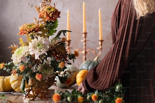 a woman arranging flowers in a vase on a table