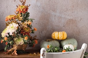 a table topped with pumpkins and flowers on top of a wooden table