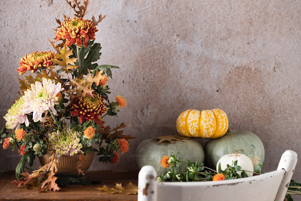 a table topped with pumpkins and flowers on top of a wooden table