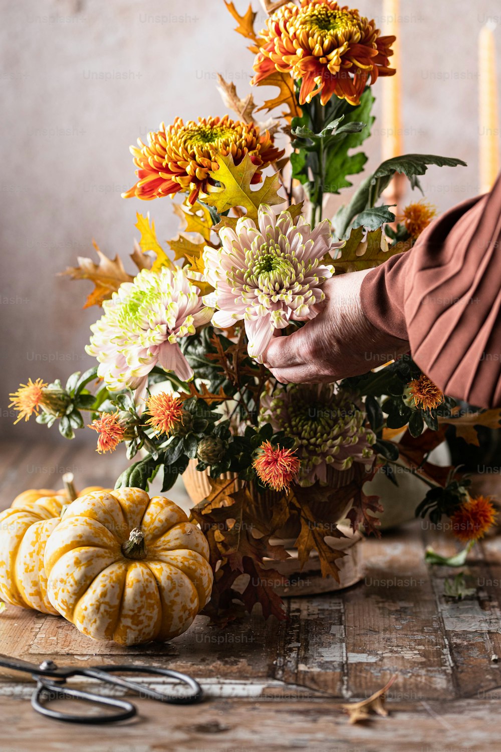 a person arranging flowers on a table with a pair of scissors