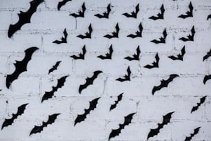 Uno stormo di pipistrelli che volano su un muro di mattoni bianchi