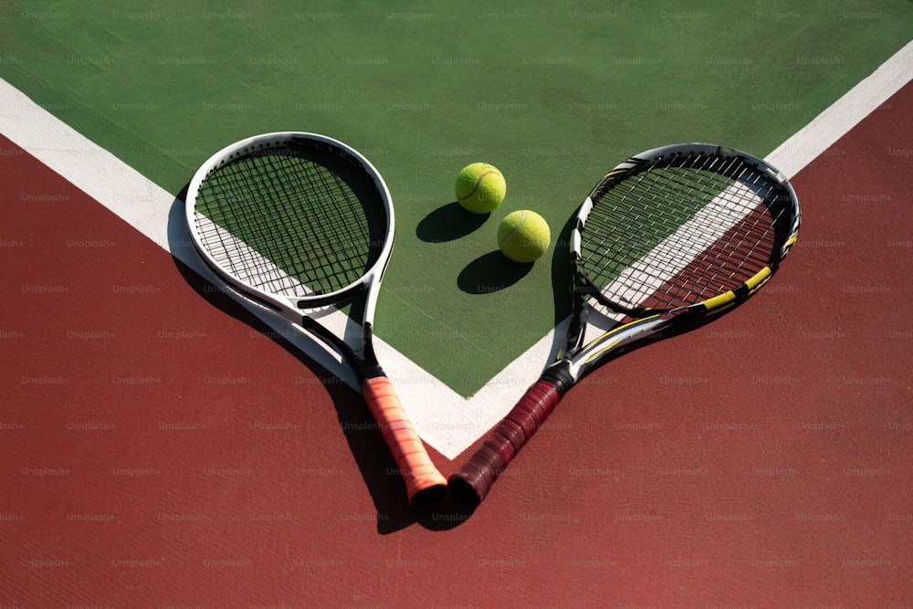 zwei Tennisschläger und zwei Tennisbälle auf einem Tennisplatz